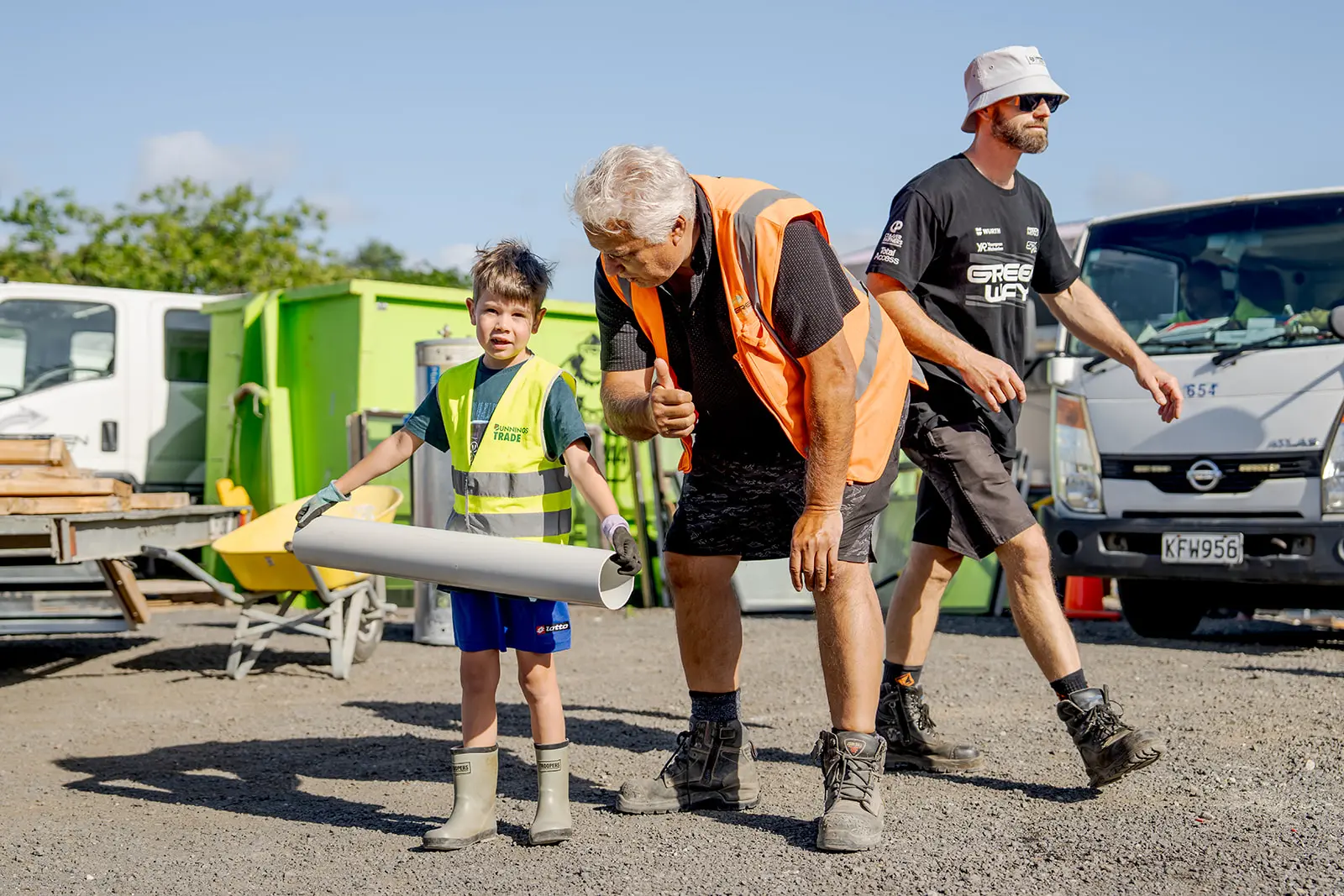 Construction worker giving thumbs up beside boy holding salvaged material