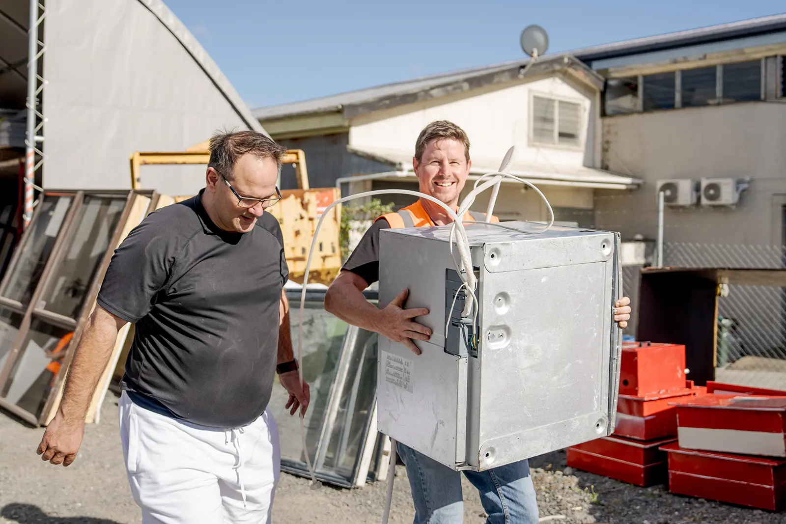 Smiling worker carrying salvaged dishwasher for community member