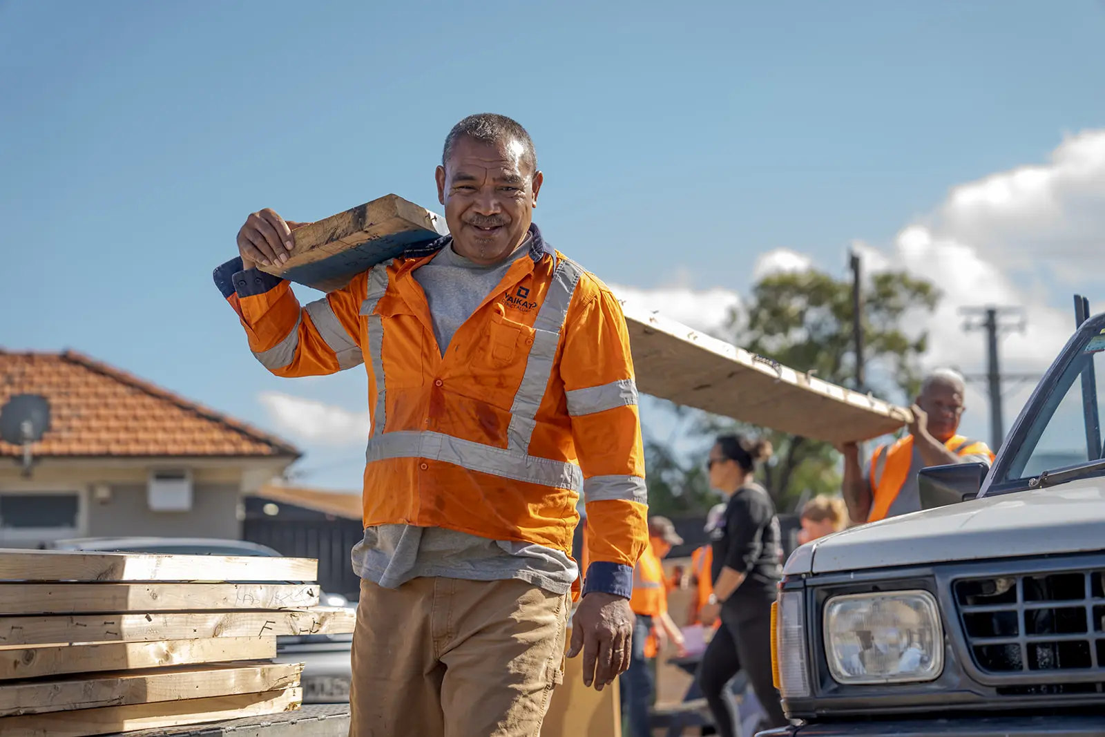 Community members carry salvaged timber for reuse